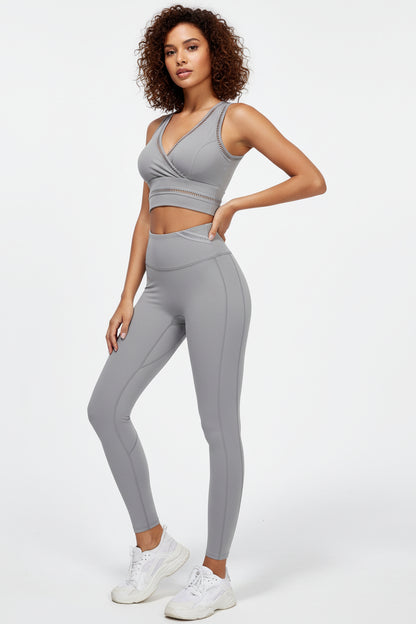 A female model wearing a white outfit consisting of a sports bra and leggings, holding a pink exercise ball, against a white background.