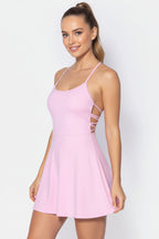 Woman wearing a pink dress with thin straps on a light gray background
