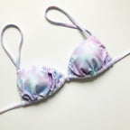 Tie-dye bikini top with pink straps on a wooden surface