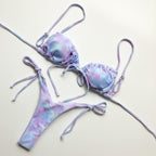 Tie-dye bikini set on a wooden surface with decorative elements.